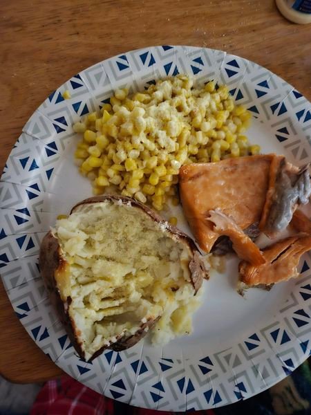 A simple meal of baked potato, corn, and salmon